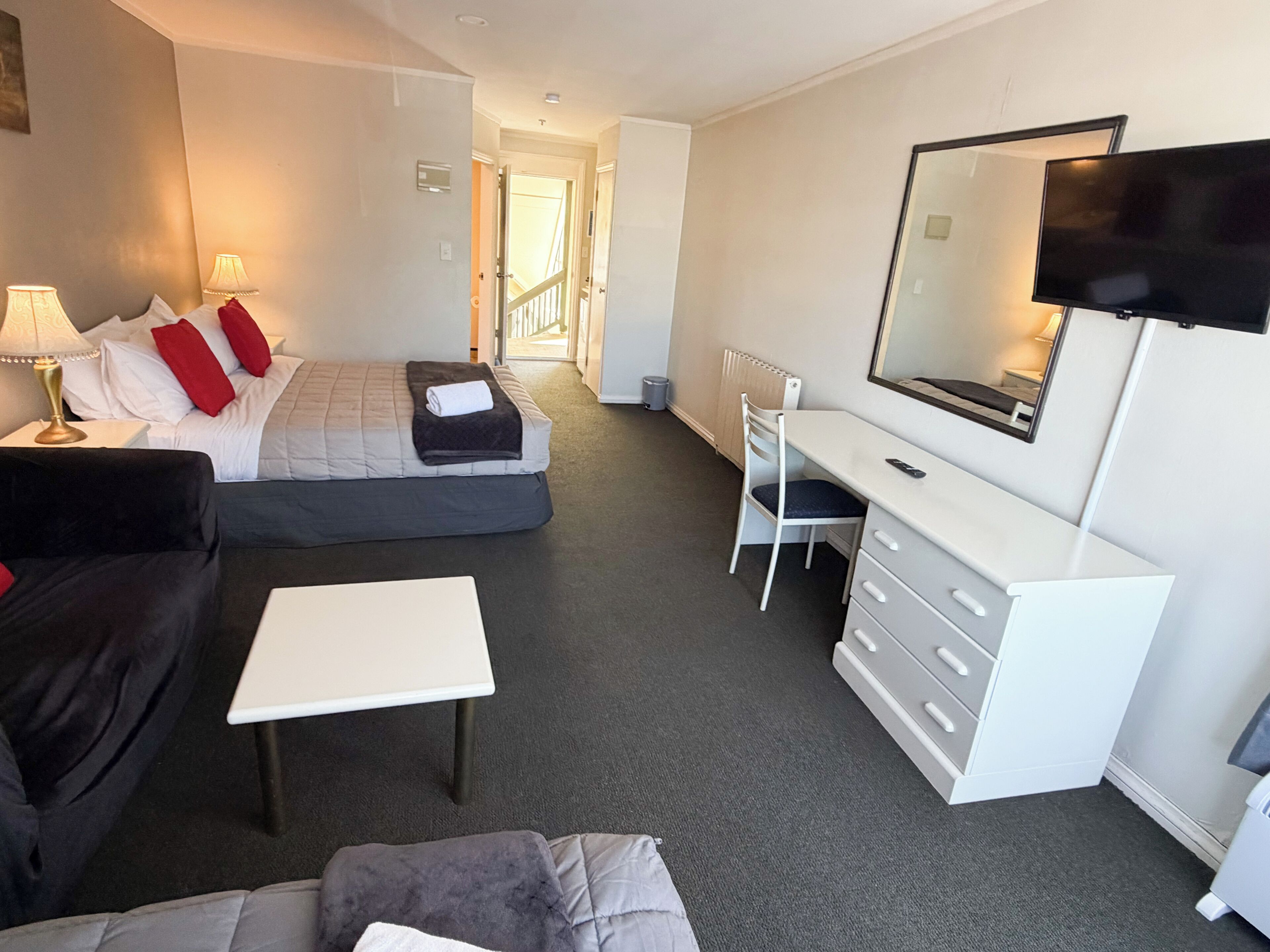 A hotel room with a bed, a desk, a chair, a TV, and a window.