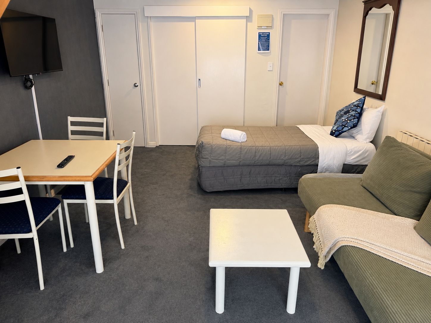 Una habitación de hotel con una cama, un sofá, una mesita y un escritorio con sillas.