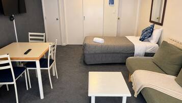 Una habitación de hotel con una cama, un sofá, una mesita y un escritorio con sillas.