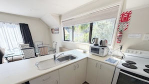 A modern kitchen with a sink, microwave, kettle, and stove. - Champers Motor Inn (Lower Hutt)