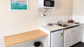 Una kitchenette compacta con microondas, pileta y heladera.
