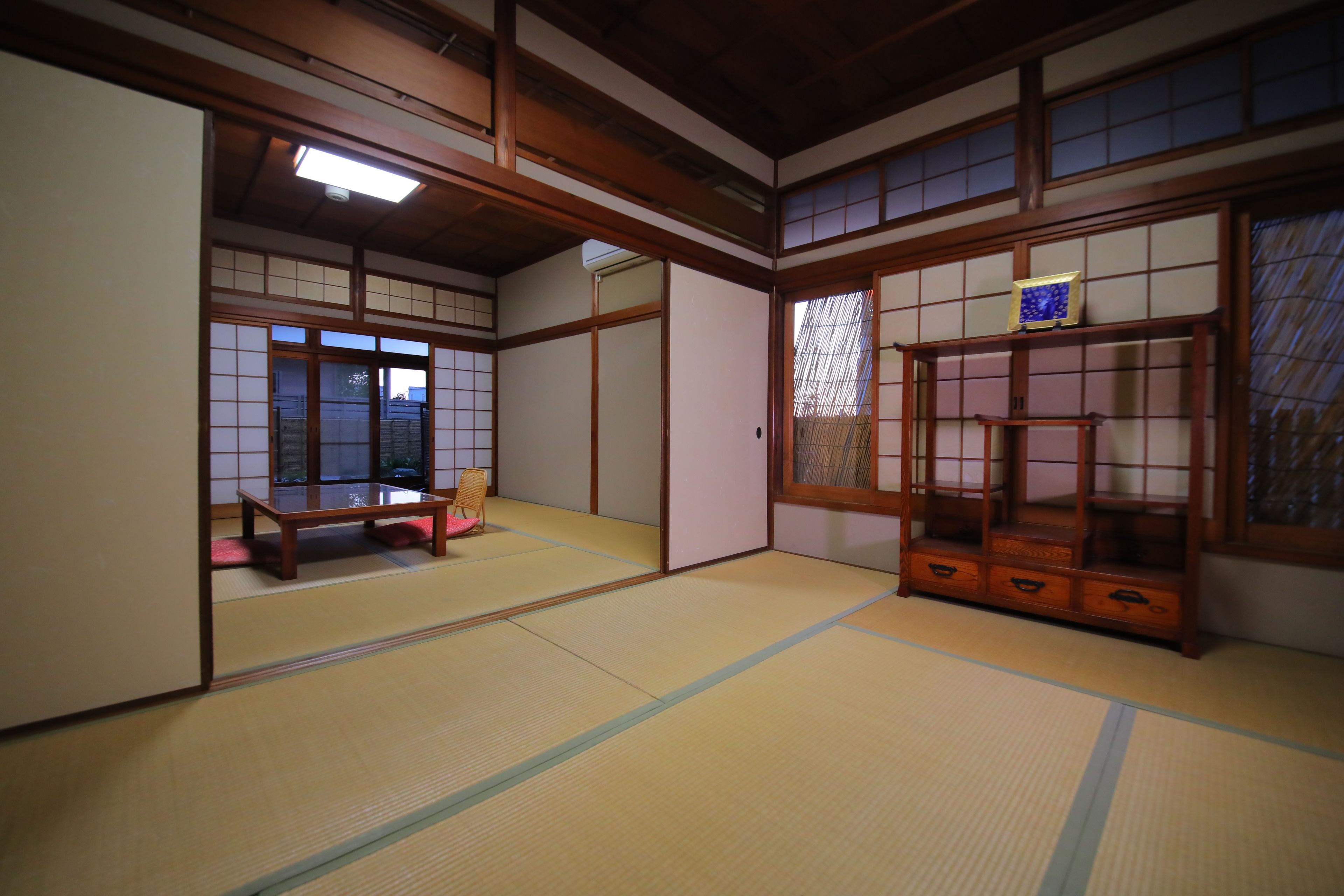 Ein traditioneller japanischer Raum mit Tatami-Böden, Schiebetüren und einem niedrigen Holztisch.