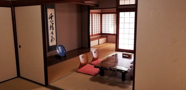A traditional Japanese room with tatami flooring, a low wooden table, and sliding doors. - Ryokan Dougoya (Matsuyama)
