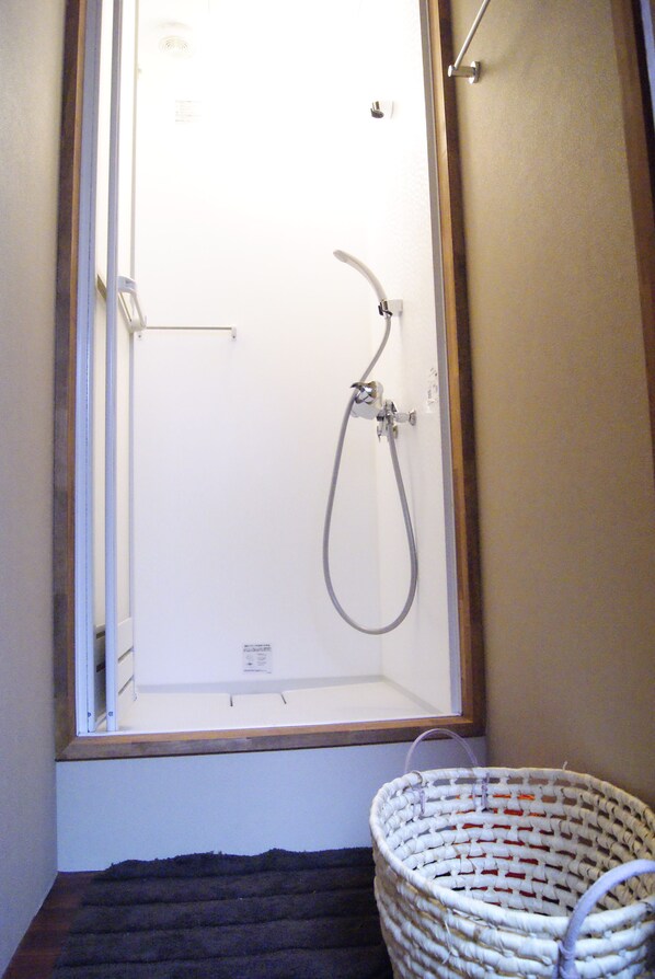 A shower with a glass door, a towel rack, and a basket. - Ryokan Dougoya (Matsuyama)