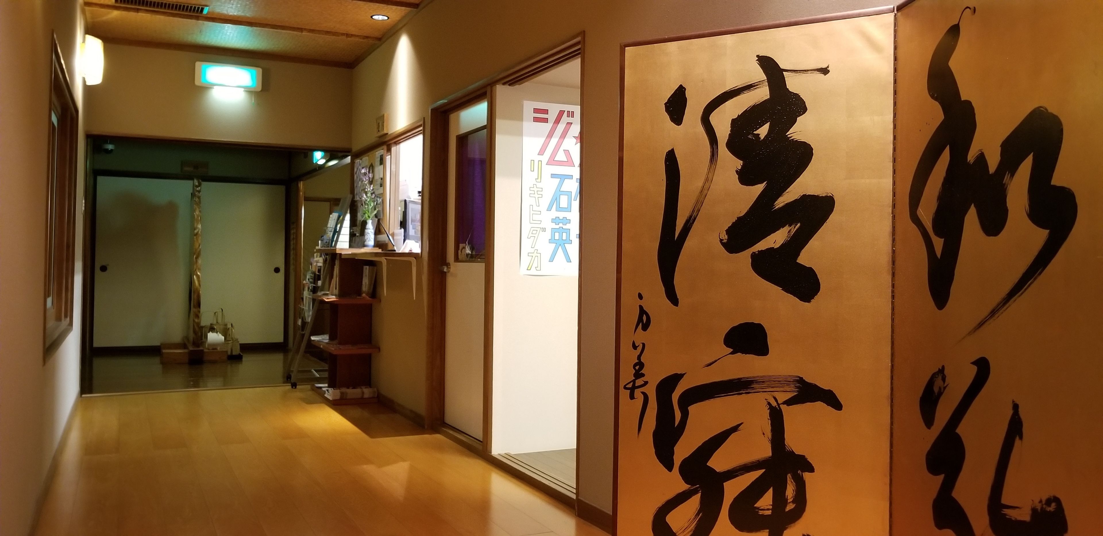 A hallway with wooden flooring, a mirror, and a door with Japanese calligraphy.