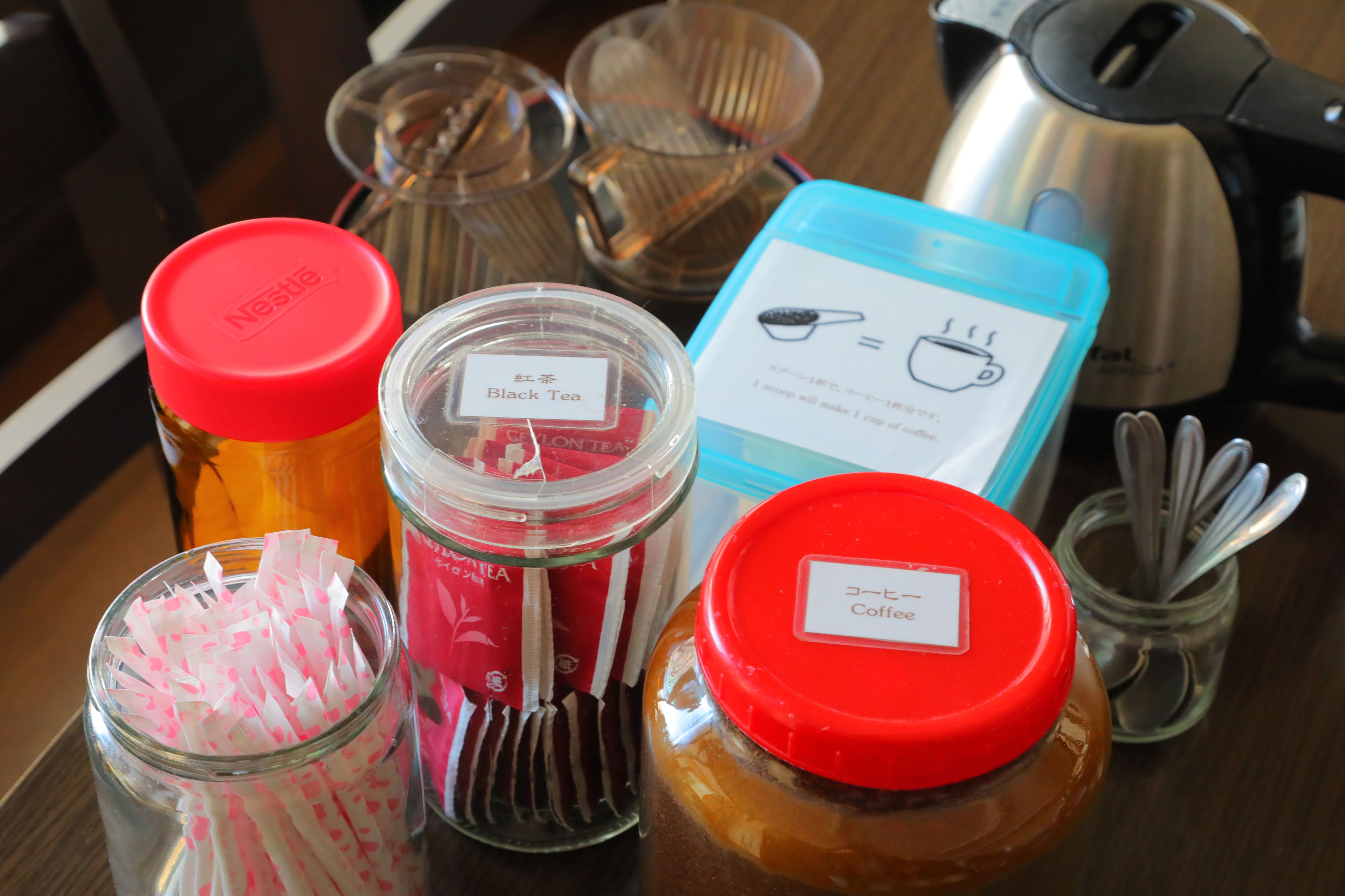 A table with various containers labeled with different types of tea and coffee, including a blue box with a coffee cup icon.