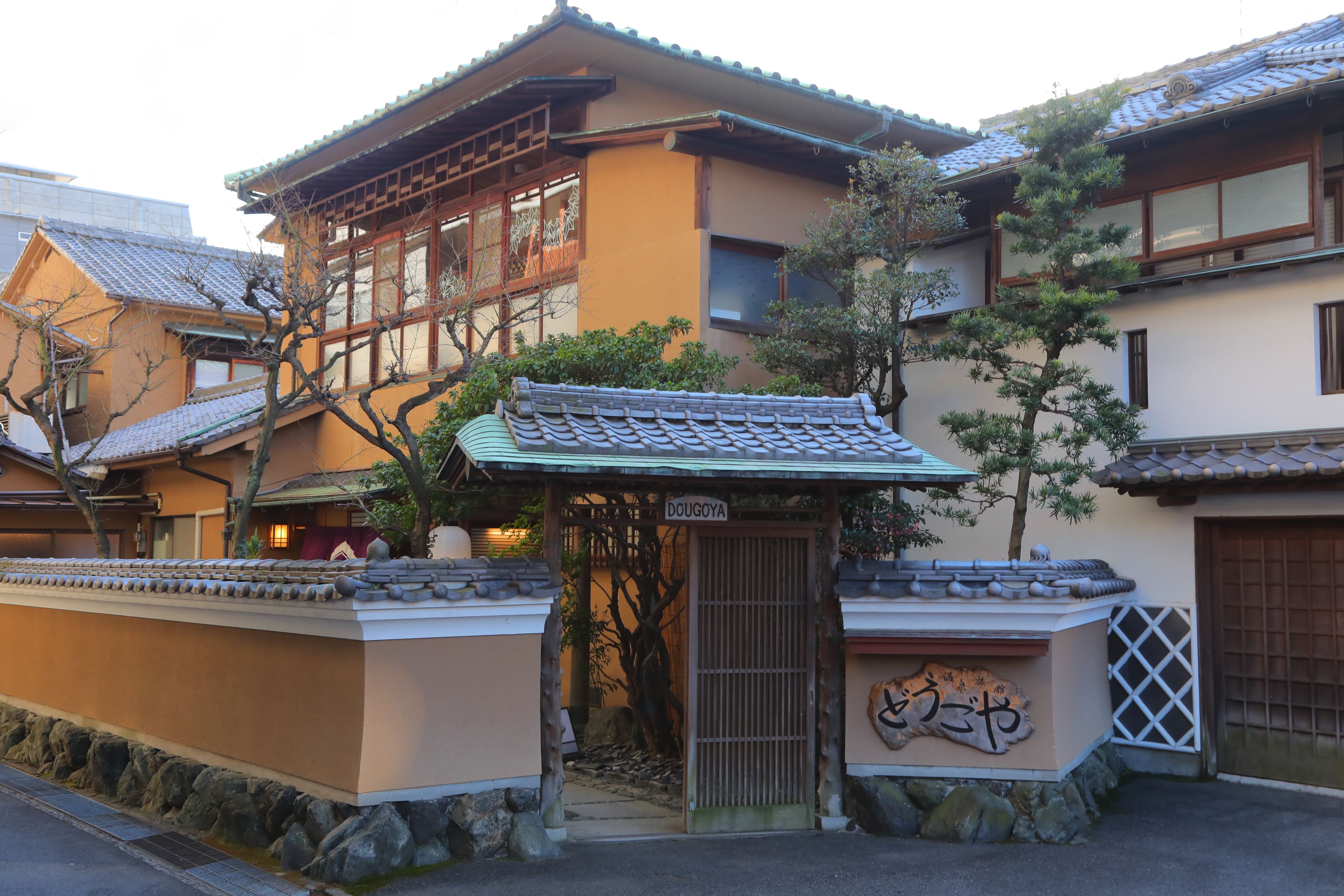 En traditionell japansk byggnad med ett tak täckt av tegelpannor, en träport och en skylt med texten ”DOUGOYA”.