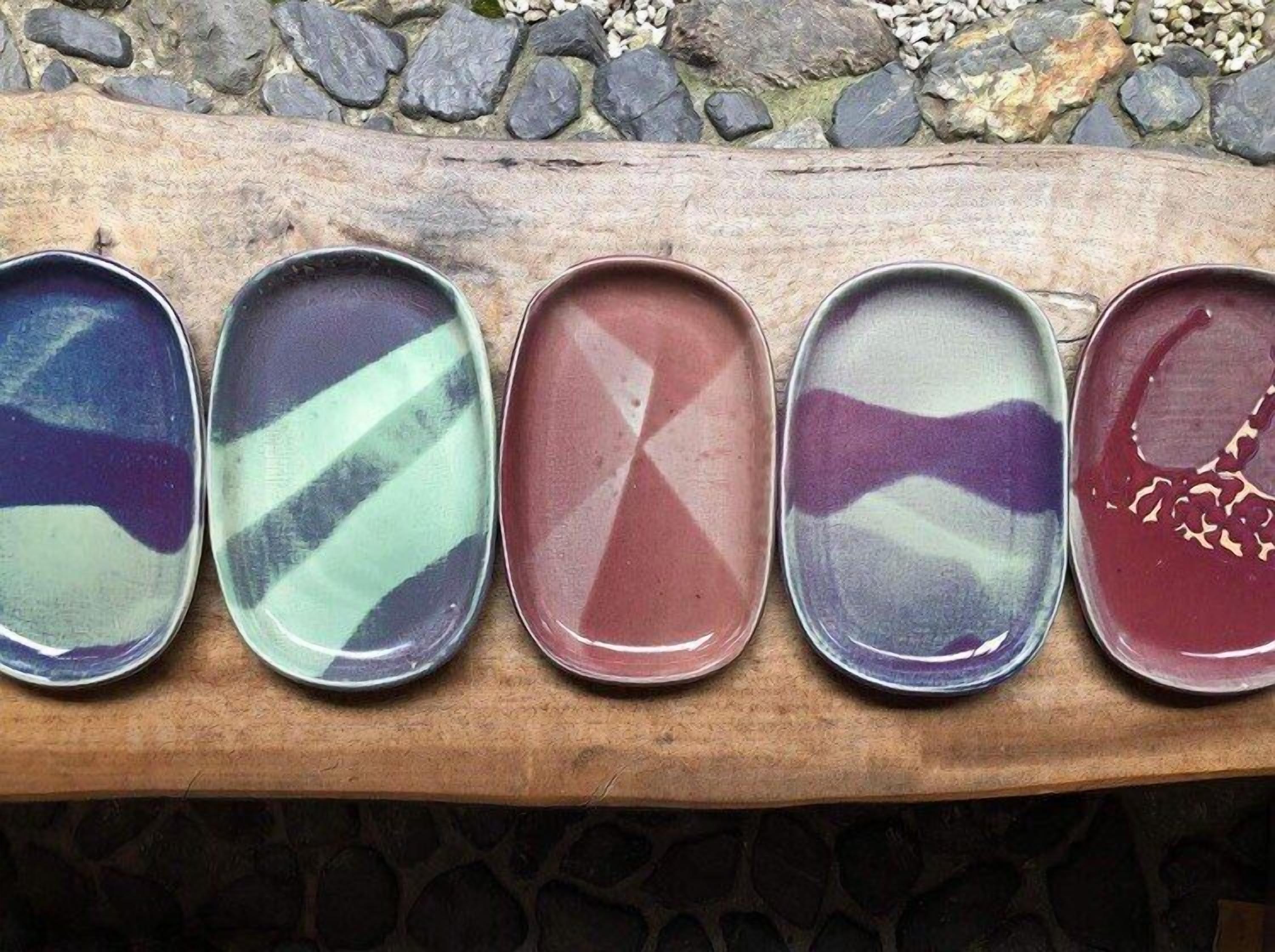 Five ceramic plates with abstract patterns on a wooden surface.