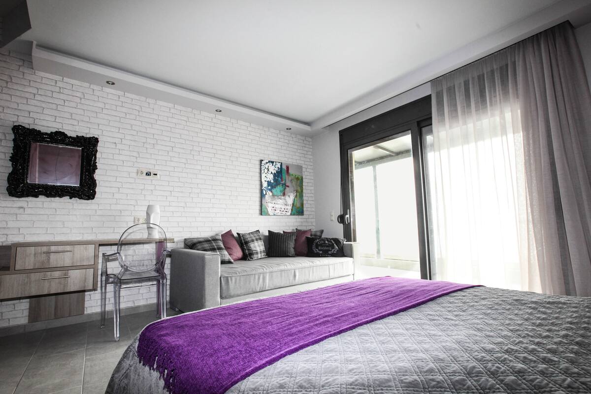 Un dormitorio moderno con una cama, un escritorio y una ventana.