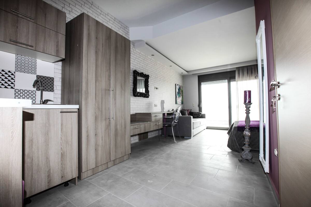 Una cocina moderna con armarios de madera, encimera blanca y salpicadero azulejado.