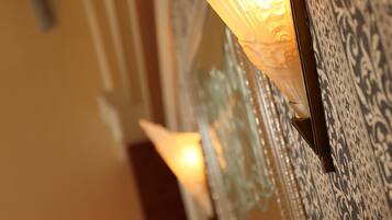 A wall-mounted light fixture with a decorative design, positioned next to a patterned wall.
