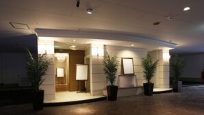 Eine Hotelhalle mit Empfangstresen, einer Kristallleuchter und Zimmerpflanzen.