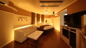 Ein Hotelzimmer mit einer Couch, einem kleinen Tisch, einem Fernseher und einem Bett.
