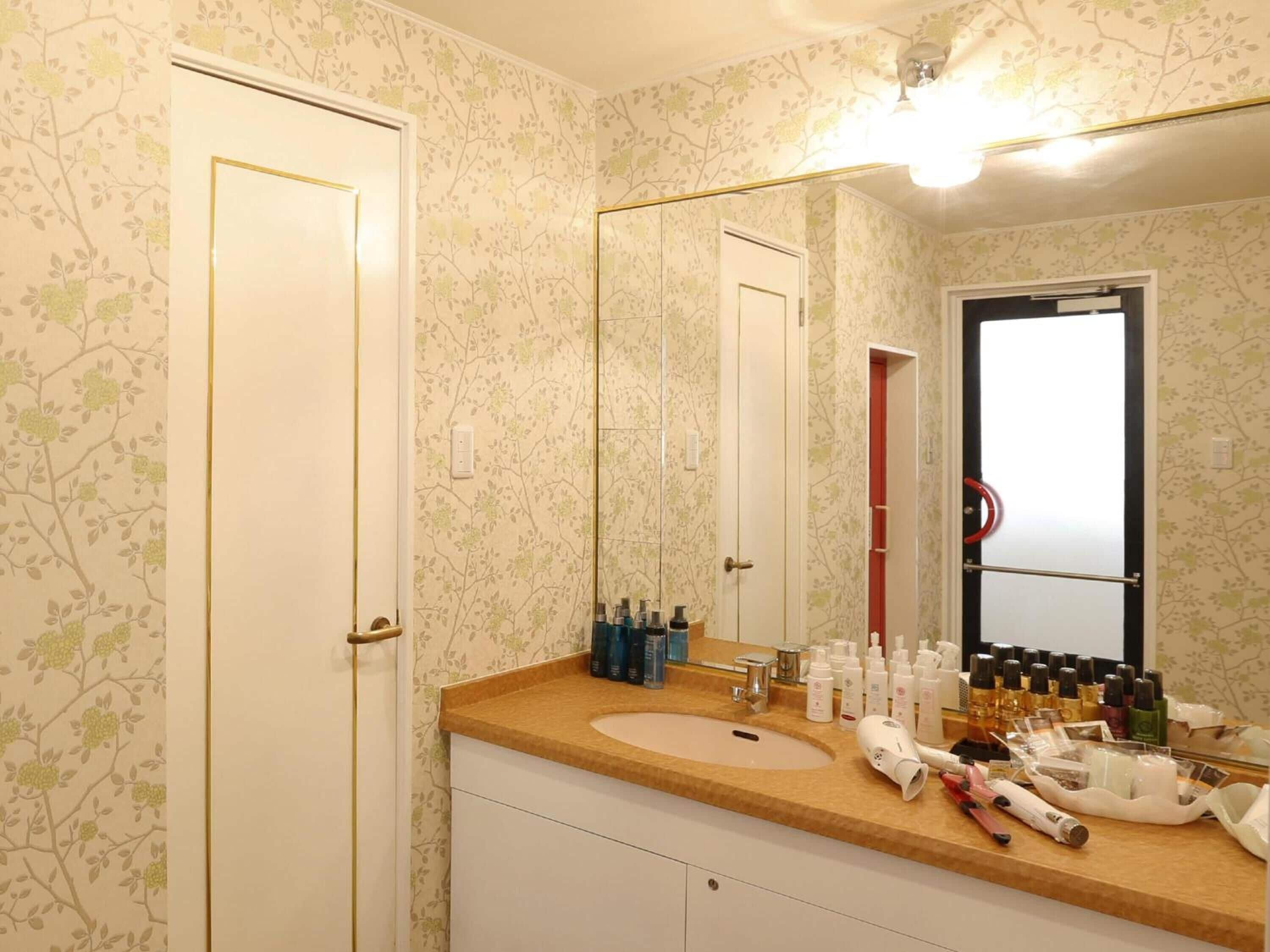 Un baño con lavamanos, espejo y artículos de aseo.