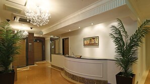 Eine Hotelhalle mit Empfangsbereich, einer Kristallleuchter und Topfpflanzen.
