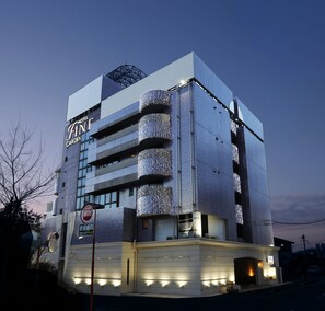 Ein mehrstöckiges Hotel mit modernem Design, mit Balkonen mit Lichterketten, einer gut sichtbaren Beschilderung und einem gut beleuchteten Eingang.