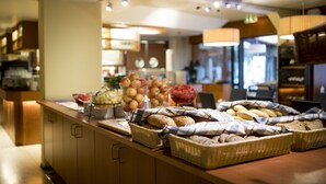 A buffet area with various food items and baskets of bread. - Hotel Savoy (Mariehamn)