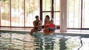 A swimming pool with people sitting by the edge. - Hotel Savoy (Mariehamn)