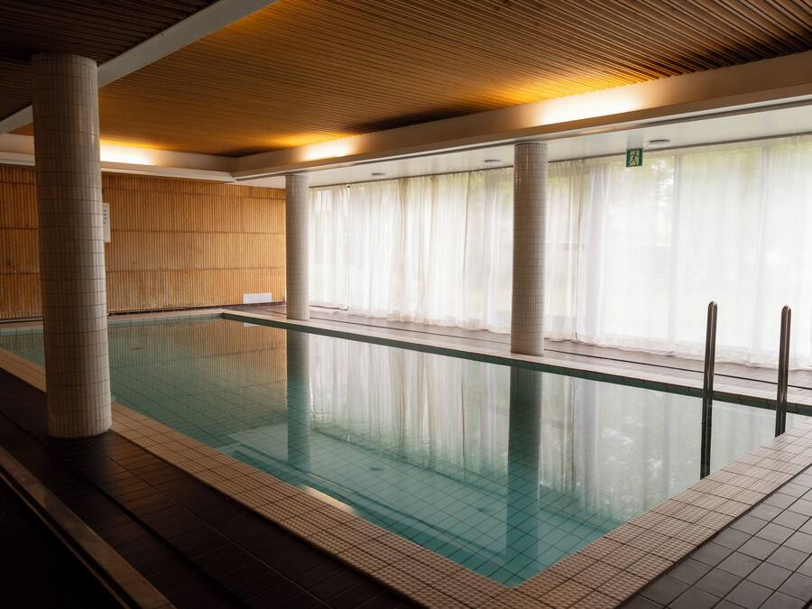 Una piscina techada con paredes de azulejos y techo de madera.