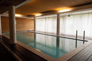 Una piscina techada con paredes de azulejos y techo de madera.