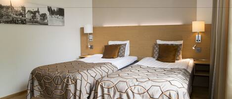 Una habitación de hotel con dos camas, cabeceros de madera y lámparas de pared.
