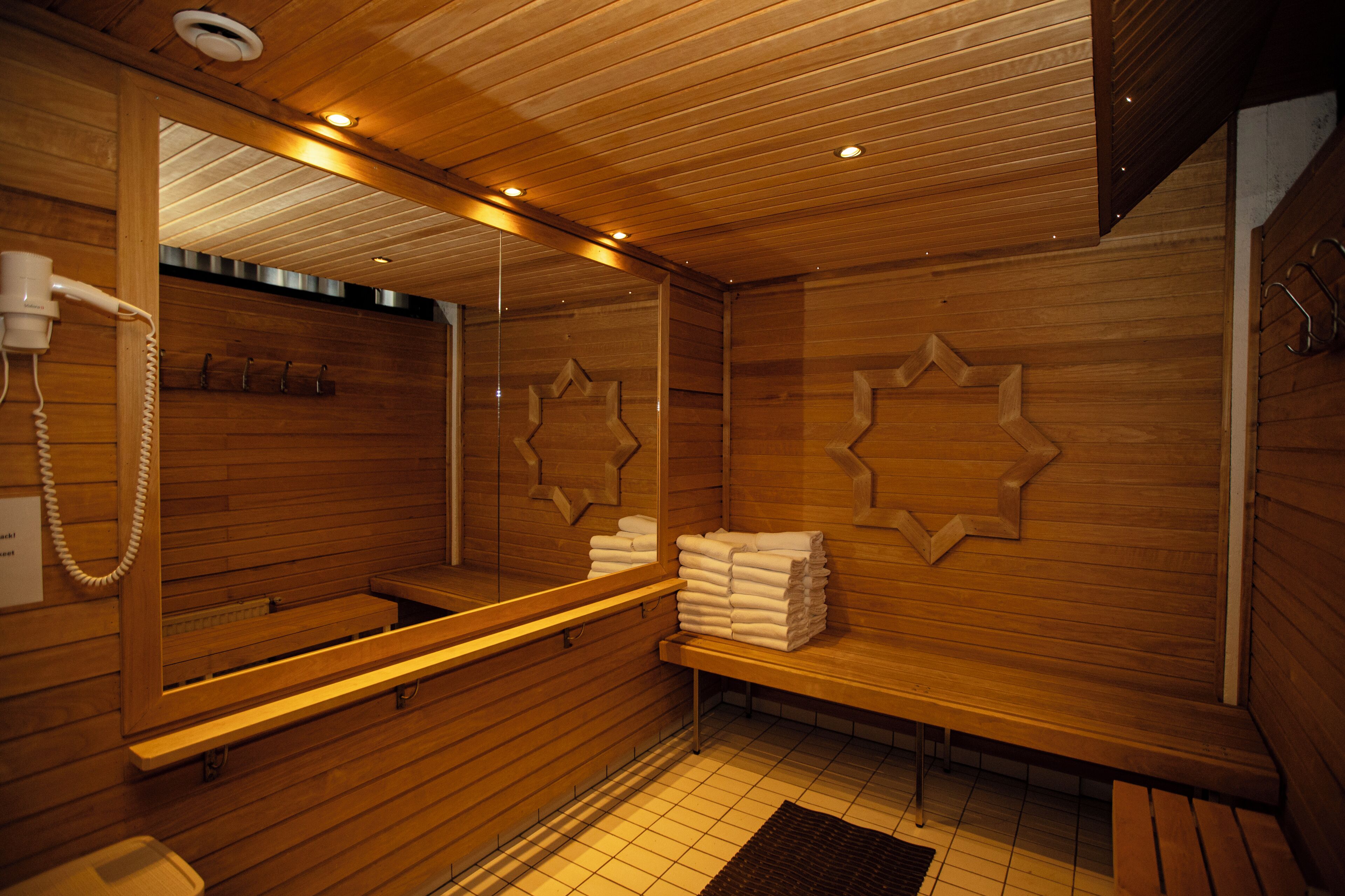 A sauna with wooden walls, a bench, a mirror, and towels.