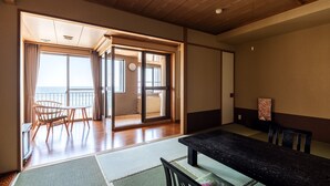 Een traditionele Japanse kamer met tatami vloerbedekking, een lage tafel met een zwart blad en houten stoelen.