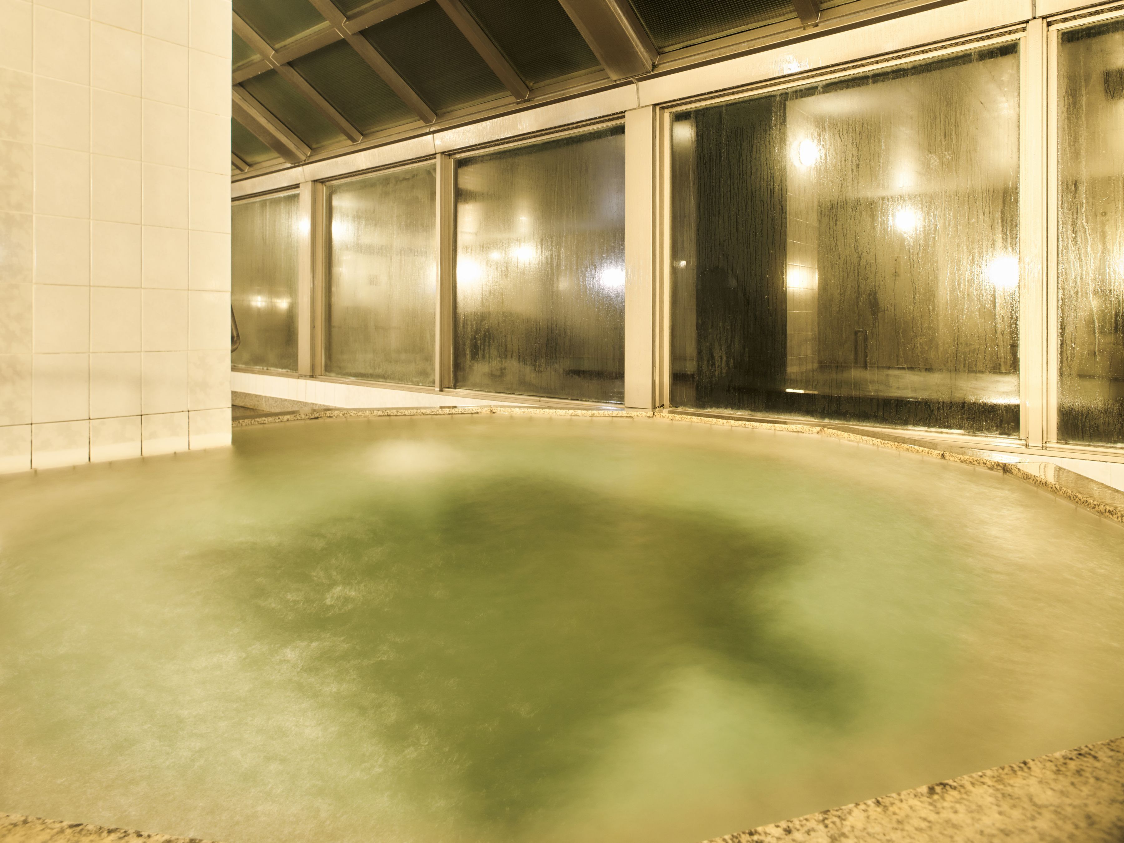 A large indoor swimming pool with a smooth, reflective surface and a tiled floor.