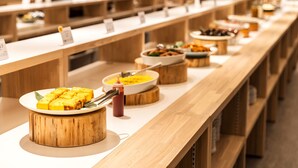 Een buffetopstelling met diverse gerechten op houten presentatietafels en witte borden.