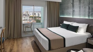 Ein Hotelzimmer mit einem großen Bett, Blick durch eine Schiebetür, einem Bild an der Wand und Holzboden.