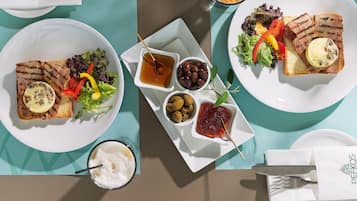 A table set with plates of food, including grilled meat, vegetables, and condiments.