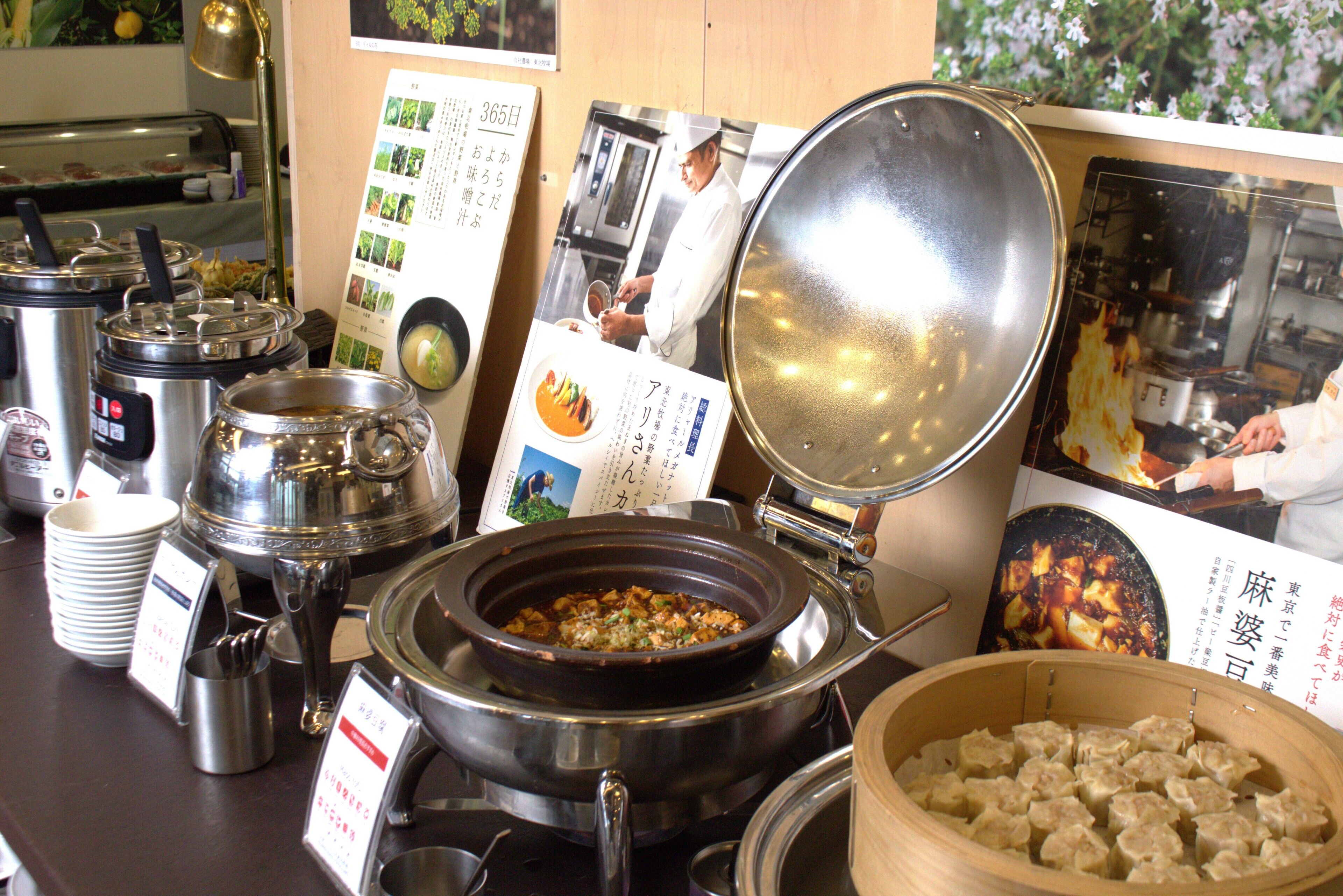 A buffet setup with various food containers and a menu board.