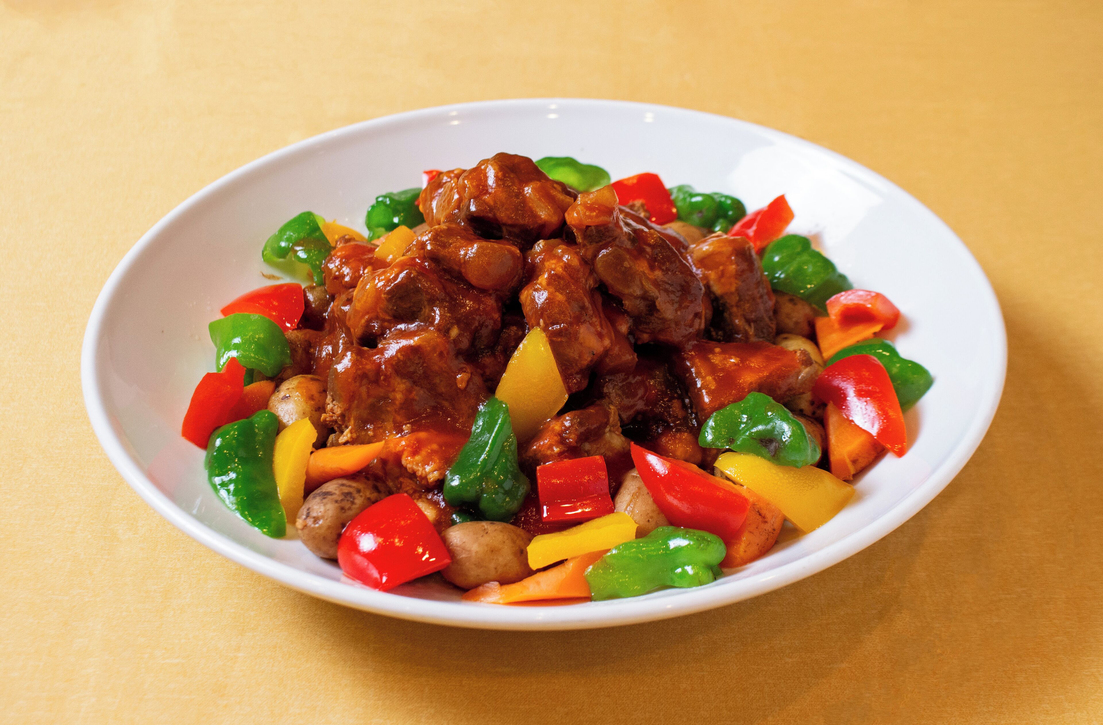 Un piatto bianco con carne e verdure saltate in padella.