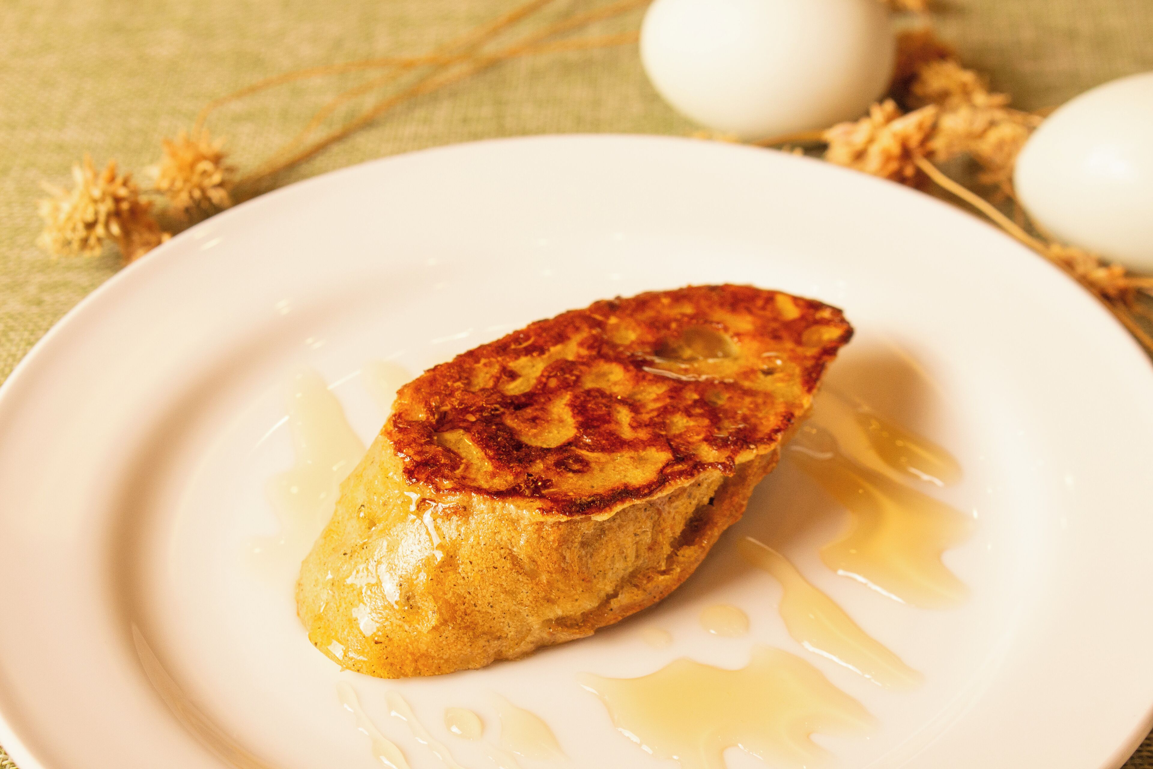 A single pancake on a white plate with syrup.
