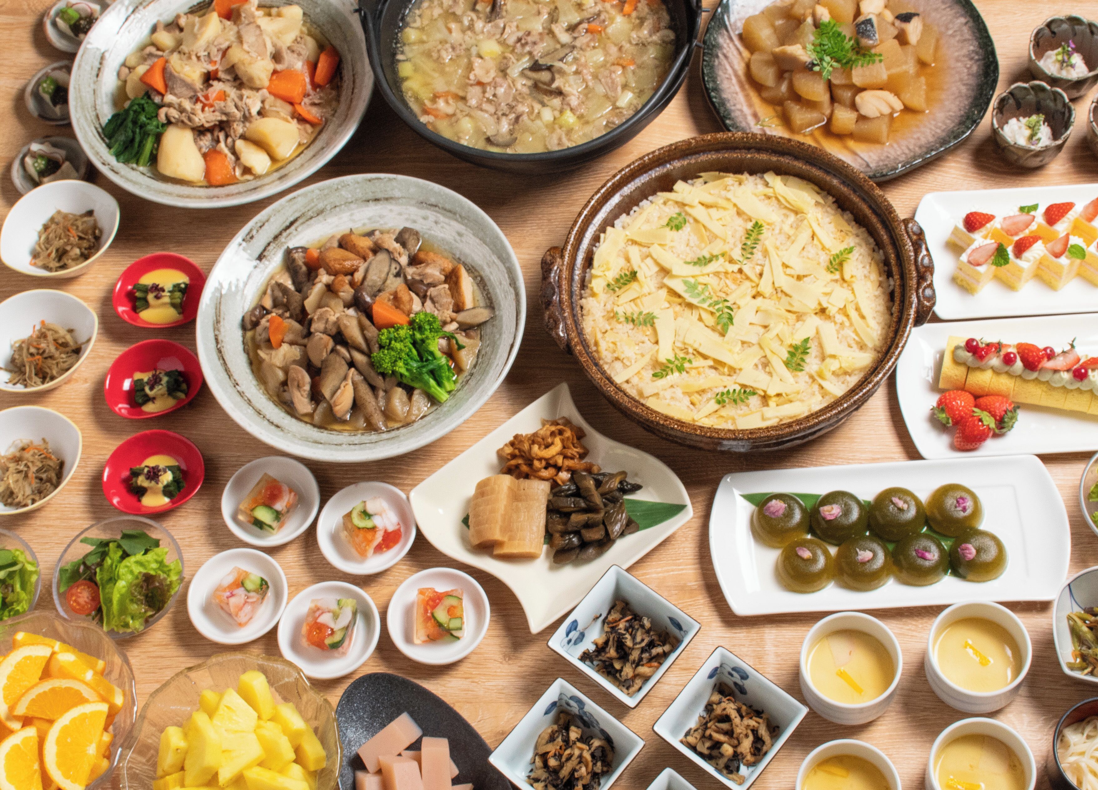 A variety of dishes including soups, salads, and desserts arranged on a wooden table.