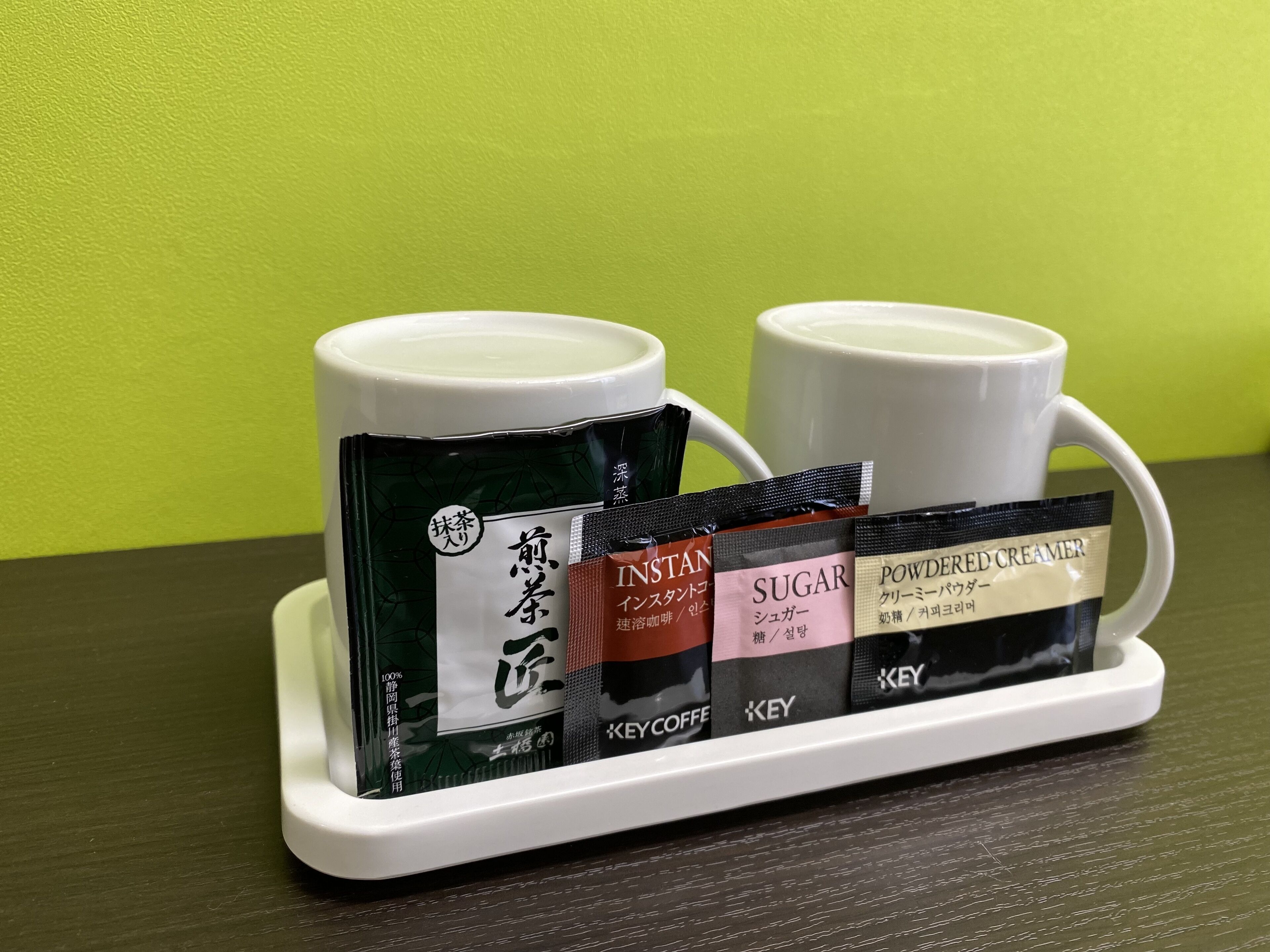 A tray with two white cups and a set of instant coffee packets.