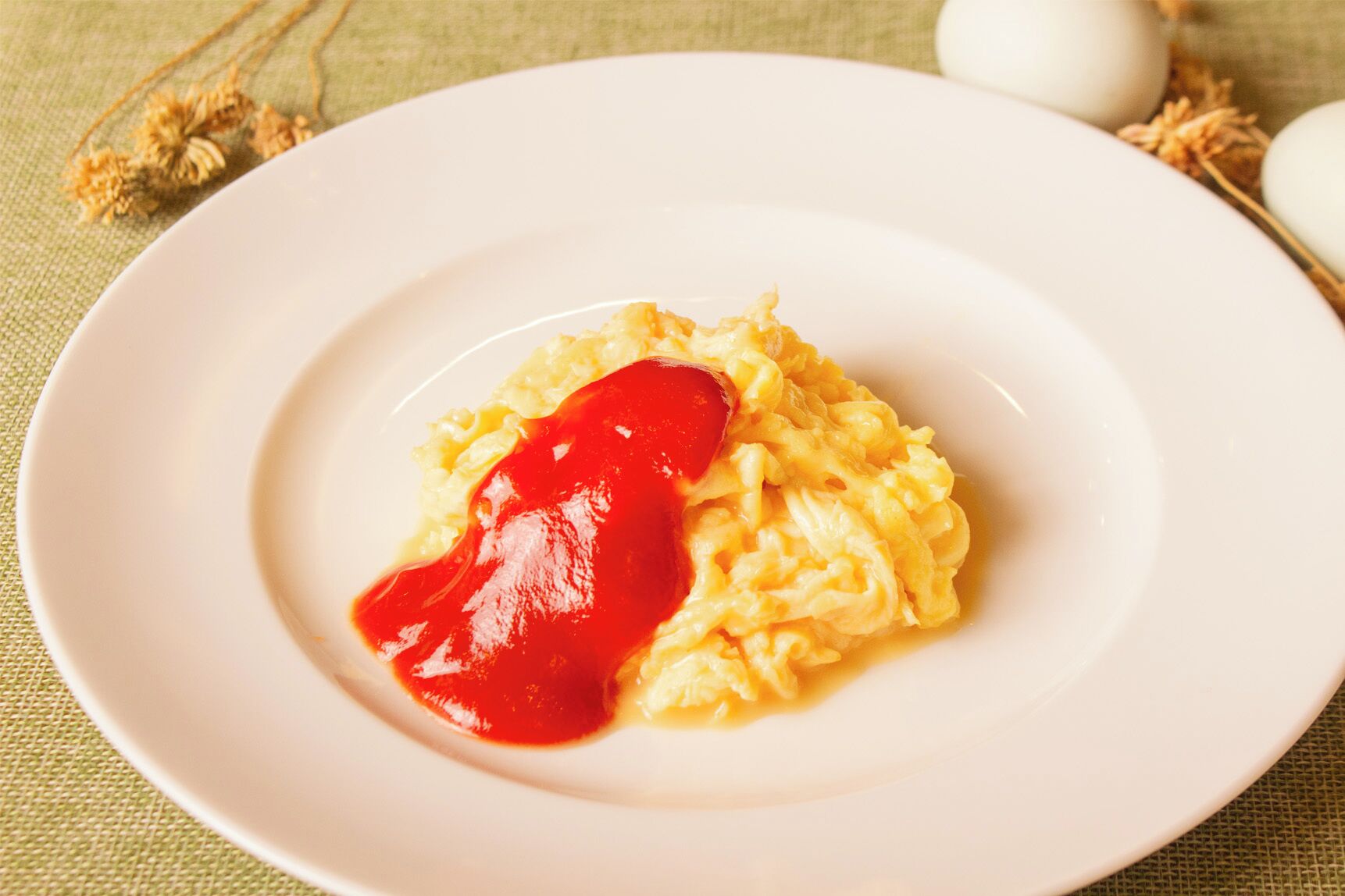 Scrambled eggs with ketchup on a white plate.