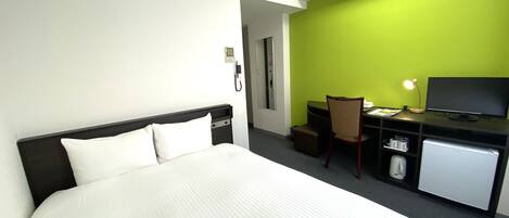 A hotel room with a bed, desk, chair, and a television.