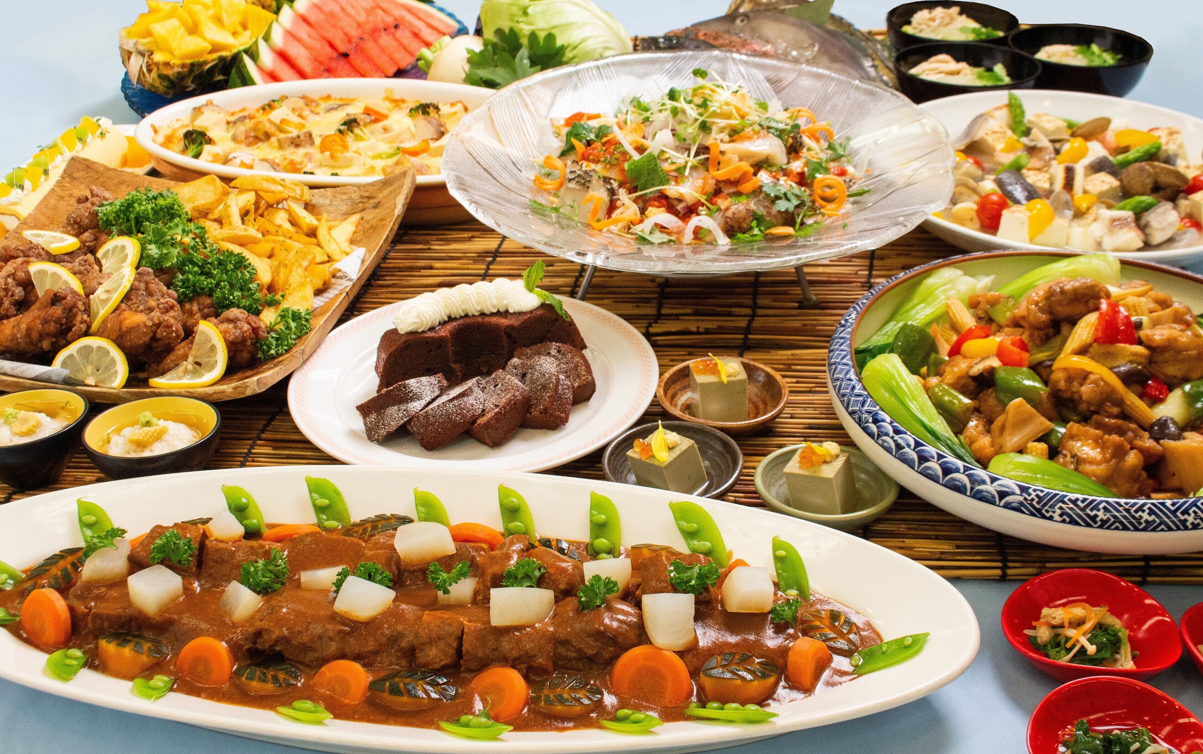A variety of dishes including a beef stew, fried chicken, and a salad.