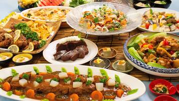 A variety of dishes including a beef stew, fried chicken, and a salad.