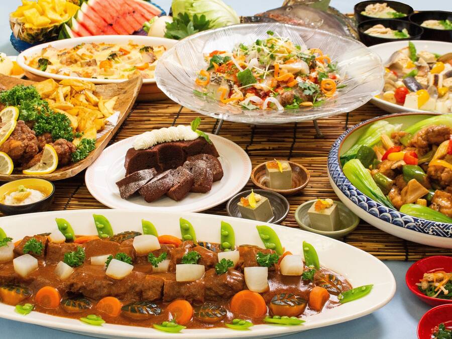 A variety of dishes including a beef stew, fried chicken, and a salad.