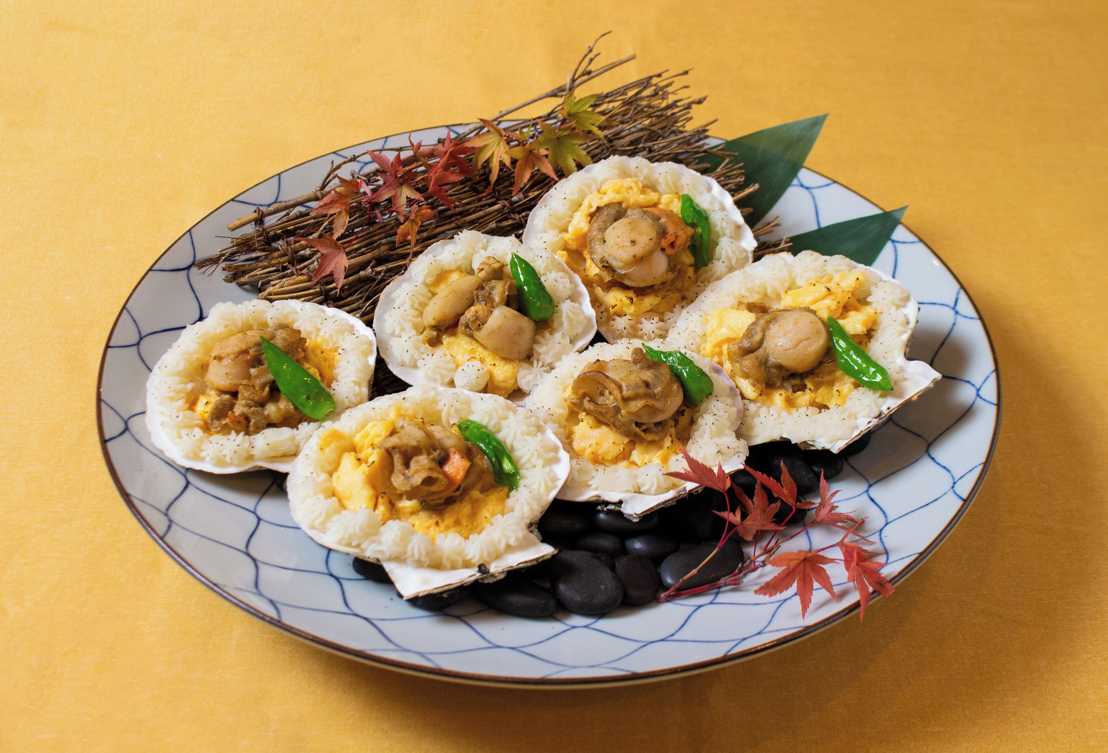 Prato de comida com arroz e diversos acompanhamentos, incluindo pimentões verdes e cogumelos, sobre um prato estampado.