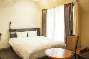 A hotel room with a bed, a round table, a chair, a telephone, and a window with curtains. - Hotel Continental (Fuchu)