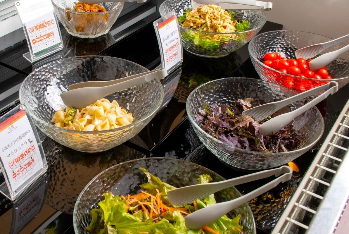 Un bufé con diversos platos, incluyendo pasta, ensaladas y verduras.