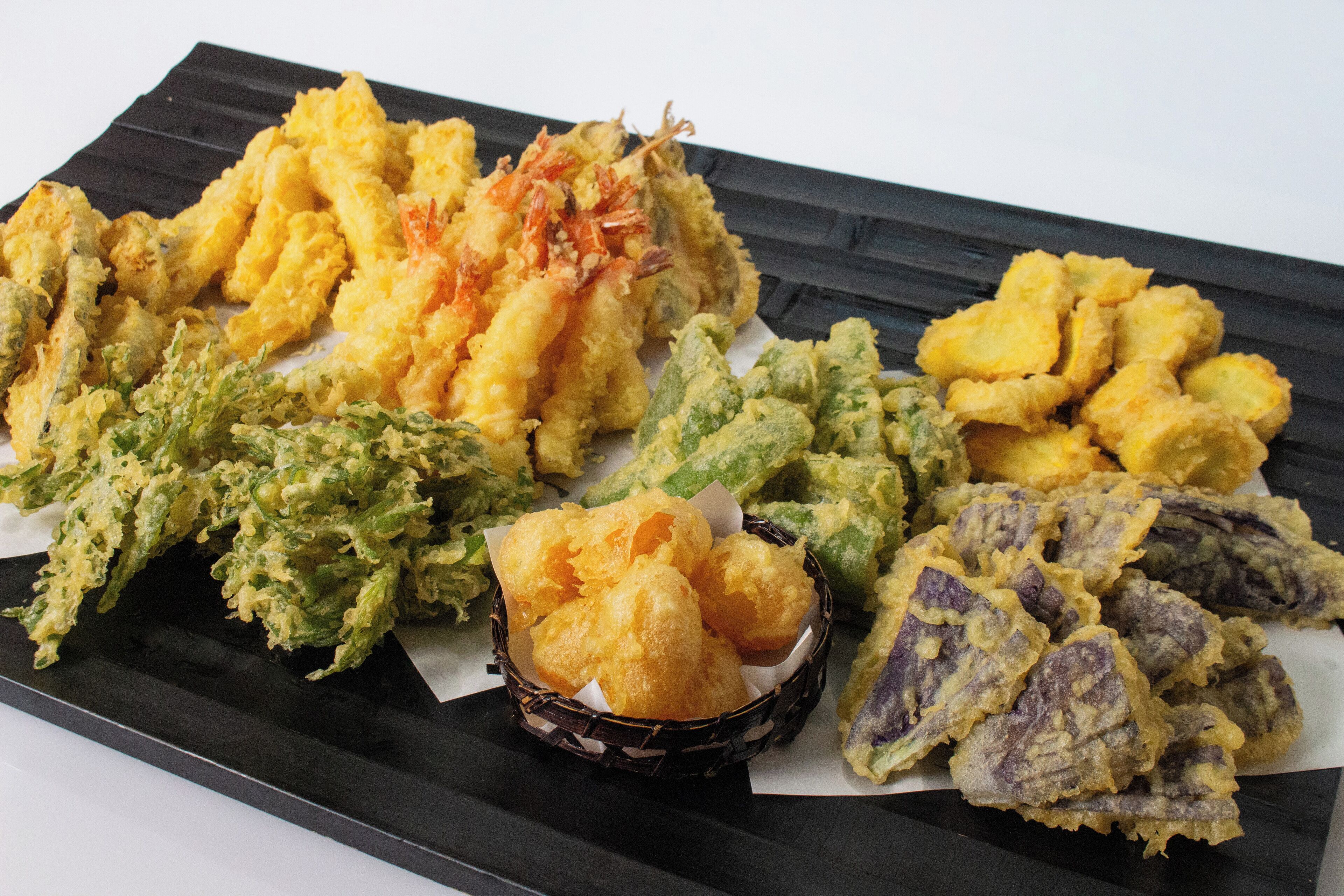 A variety of fried seafood items on a black tray.