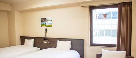 A hotel room with two single beds, a large window with curtains, and a wall-mounted phone.