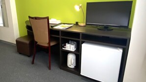 A compact workspace with a desk, chair, and a small refrigerator. - Hotel Continental (Fuchu)