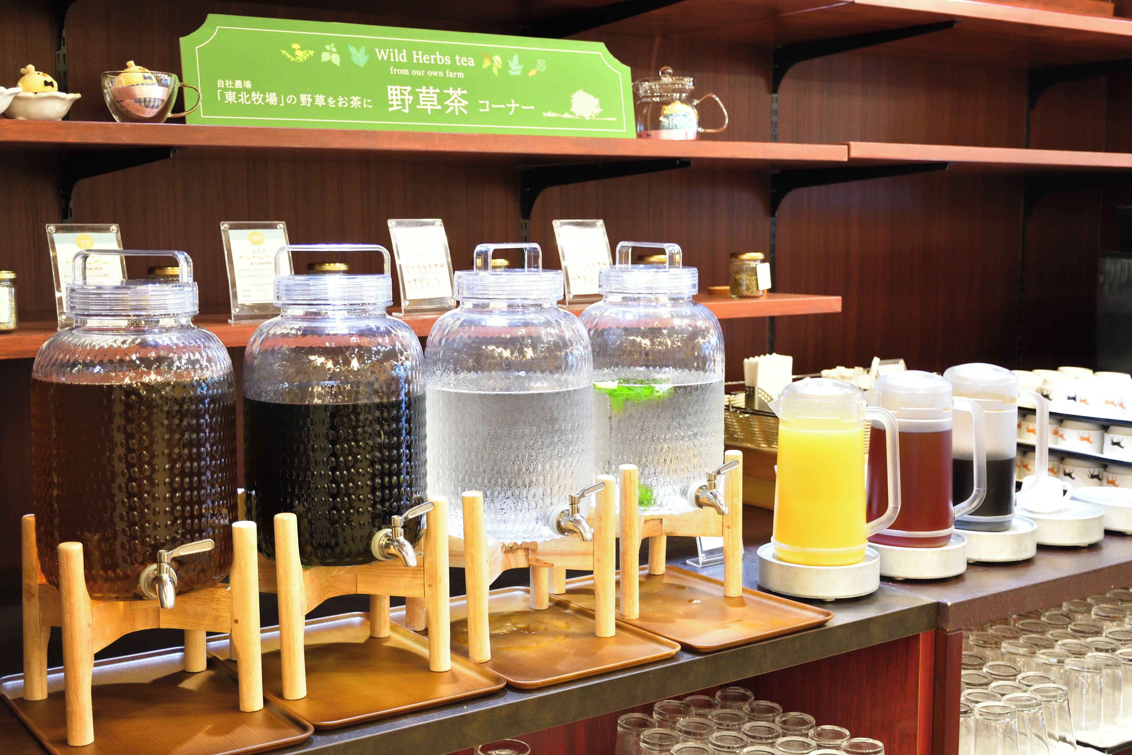 Una estación de bebidas con varios dispensadores y un cartel que indica los tipos de bebidas disponibles.