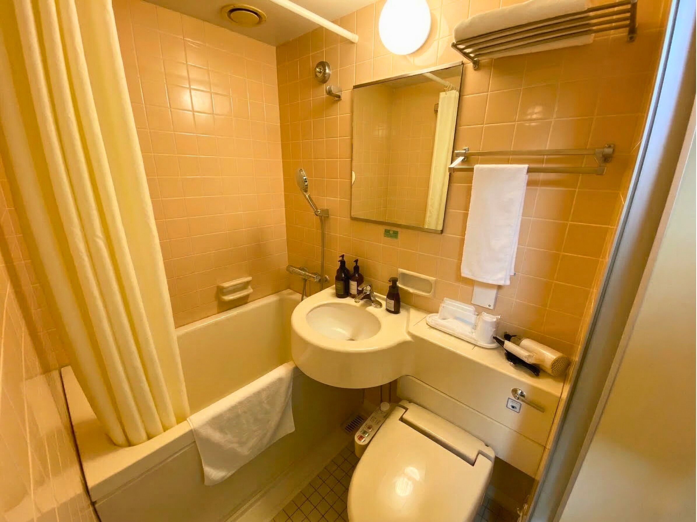 A bathroom with a bathtub, a sink, a toilet, and a mirror.