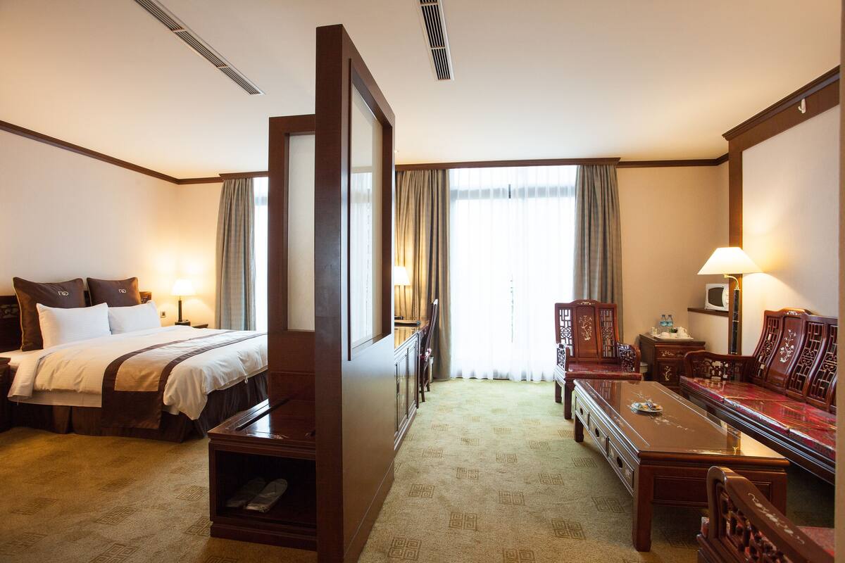 A hotel room with a bed, a desk, a sofa, and a TV.
